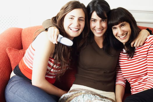 Portrait of two young women and a mid adult woman sitting on a couch and smiling
