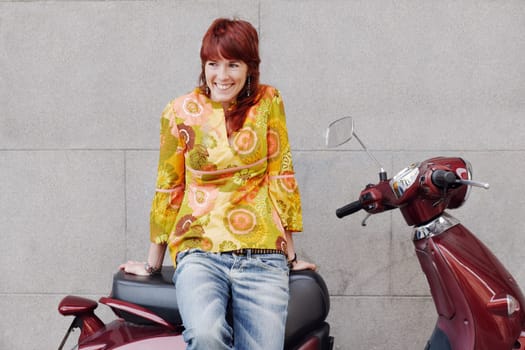 Young woman sitting on a motor scooter and smiling