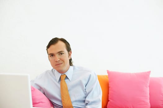 Portrait of a businessman sitting on a couch with a laptop