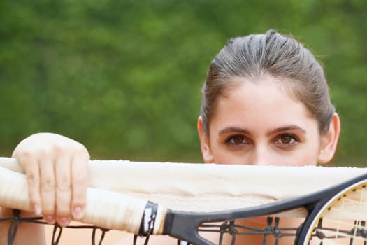 Portrait of a young woman holding a tennis racket over a tennis net