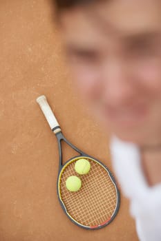 High angle view of a mid adult man with two tennis balls and a tennis racket