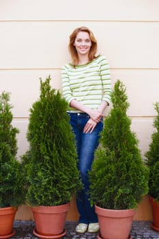 Portrait of a young woman standing behind potted plants