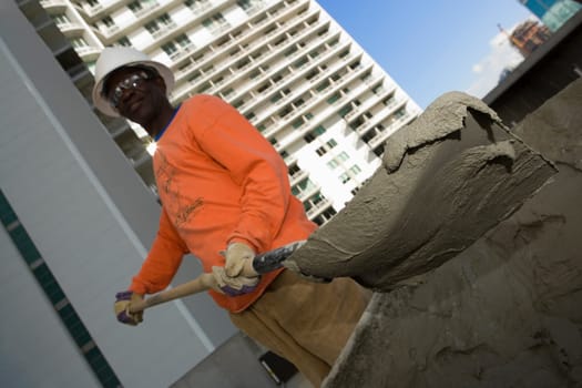 Low angle view of a male construction worker shoveling cement