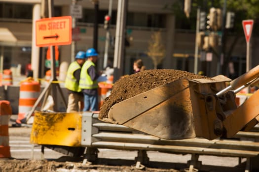 Close-up of the scoop of an earth mover carrying soil
