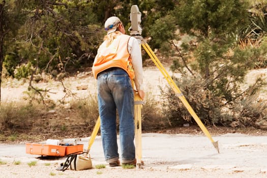 Rear view of a surveyor looking through a theodolite