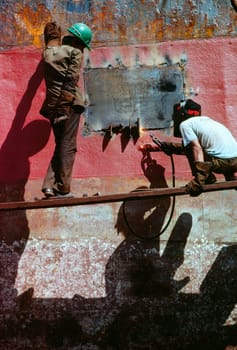Low angle view of two men welding a tanker, Cebu, Philippines
