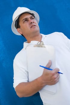 Low angle view of a male construction worker holding a clipboard and a pen