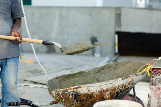 Construction worker holding a shovel with sand