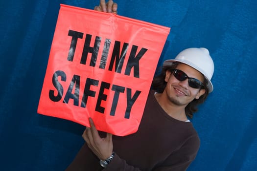 Close-up of a male construction worker smiling and holding a warning sign