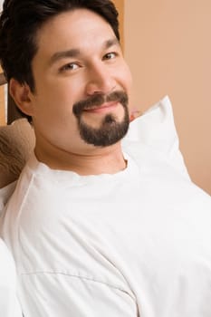 Portrait of a mid adult man reclining on the bed and smiling
