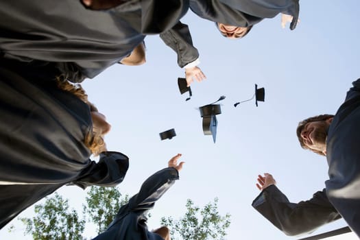 Low angle view of graduate students throwing their mortar boards in air