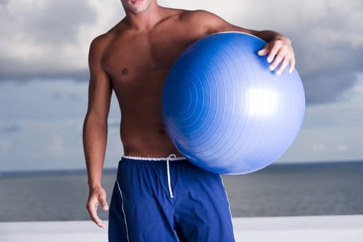 Mid section view of a man holding a fitness ball