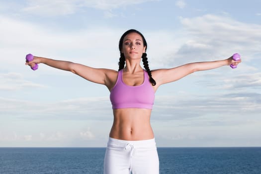 Portrait of a young woman exercising with dumbbells