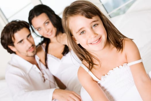 Portrait of a girl smiling with her parents behind her