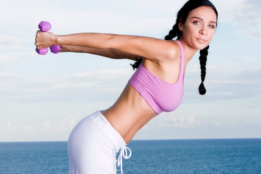 Portrait of a young woman exercising with dumbbells