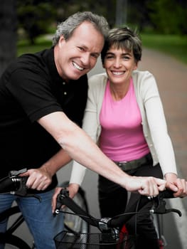 Portrait of a mature couple standing with bicycles and smiling