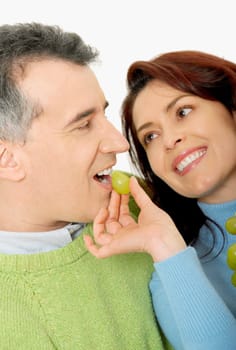 Close-up of a mid adult woman feeding a grape to a mid adult man