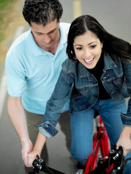 High angle view of a mid adult man helping a mid adult woman ride a bicycle