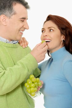 Close-up of a mid adult man feeding a grape to a mid adult woman