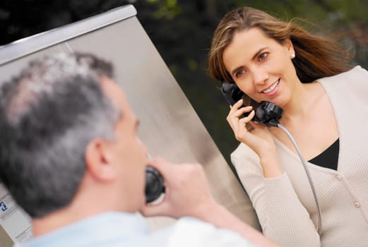 Close-up of a mid adult couple talking on a pay phone