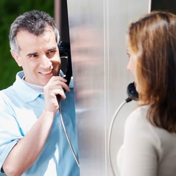 Close-up of a mid adult couple talking on a pay phone