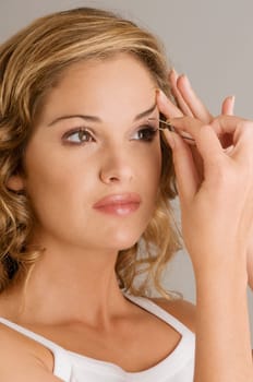Close_up of a young woman tweezing her eyebrow