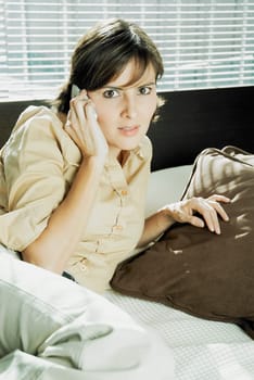 Portrait of a mid adult woman talking on a mobile phone on the bed