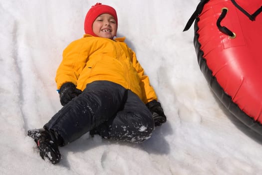 Portrait of a girl sliding with an inner tube in snow