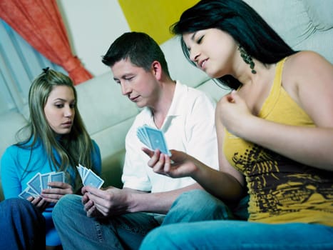 Two young women with a mid adult man playing cards