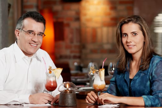 Portrait of a mid adult couple sitting in a restaurant with two glasses of pina colada