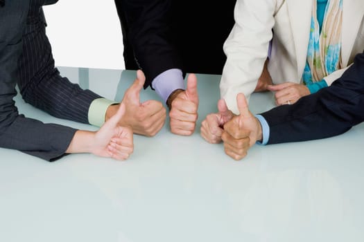 Five business executives showing thumbs up sign in a meeting