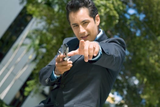 Portrait of a businessman holding a mobile phone and pointing forward