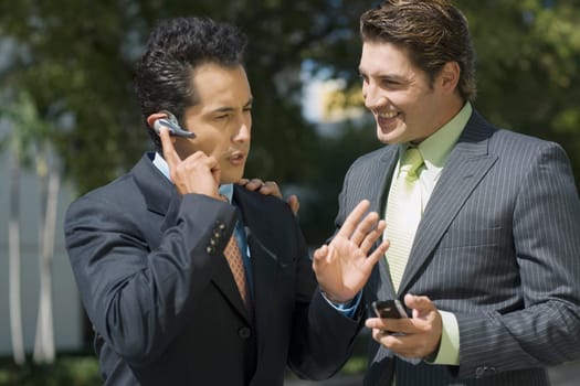 Businessman talking on a hands free device with another businessman standing beside him