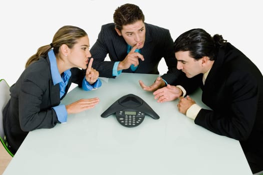 Two businessmen and a businesswoman having a telephone conference in a boardroom