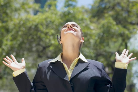 Businesswoman looking up with her arms raised