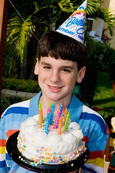 Portrait of a boy holding a birthday cake and smiling
