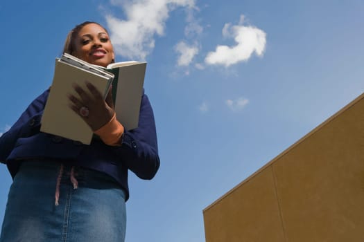 Low angle view of a young woman reading a textbook