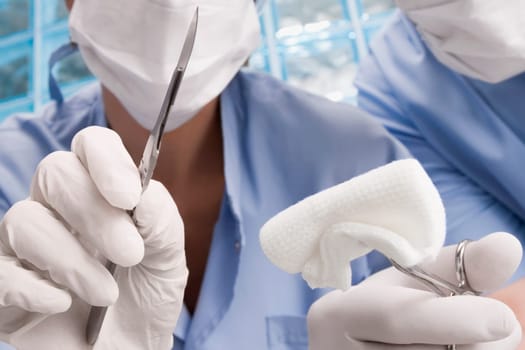 Two surgeons holding a scalpel and a surgical scissors