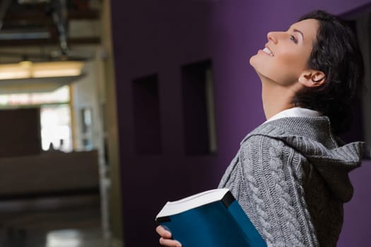 Side profile of a young woman holding a textbook