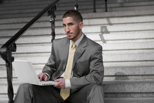 Portrait of a businessman sitting on a staircase and using a laptop