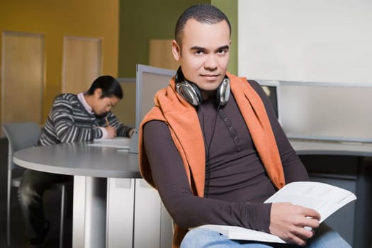 Portrait of a young man holding a book in a computer lab