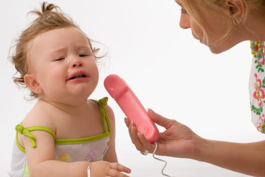 Close_up of a mid adult woman giving the receiver of a toy phone to her daughter