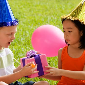 Close_up of a boy giving a birthday present to a girl