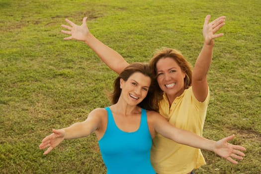 Portrait of a mid adult woman and a mature woman standing with their arms outstretched
