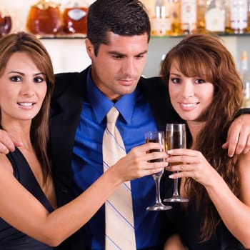 Close-up of a mid adult man with his arms over two young women