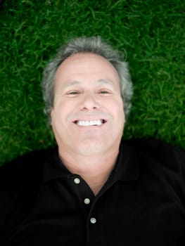 Portrait of a mature man lying on the grass and smiling