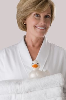 Portrait of a mature woman holding a stack of folded towels