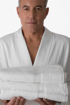 Portrait of a senior man holding a stack of folded towels