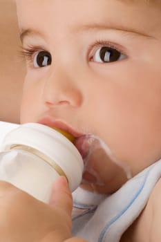 Close_up of a baby boy drinking milk from a baby bottle