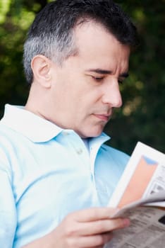 Close-up of a mid adult man reading a newspaper